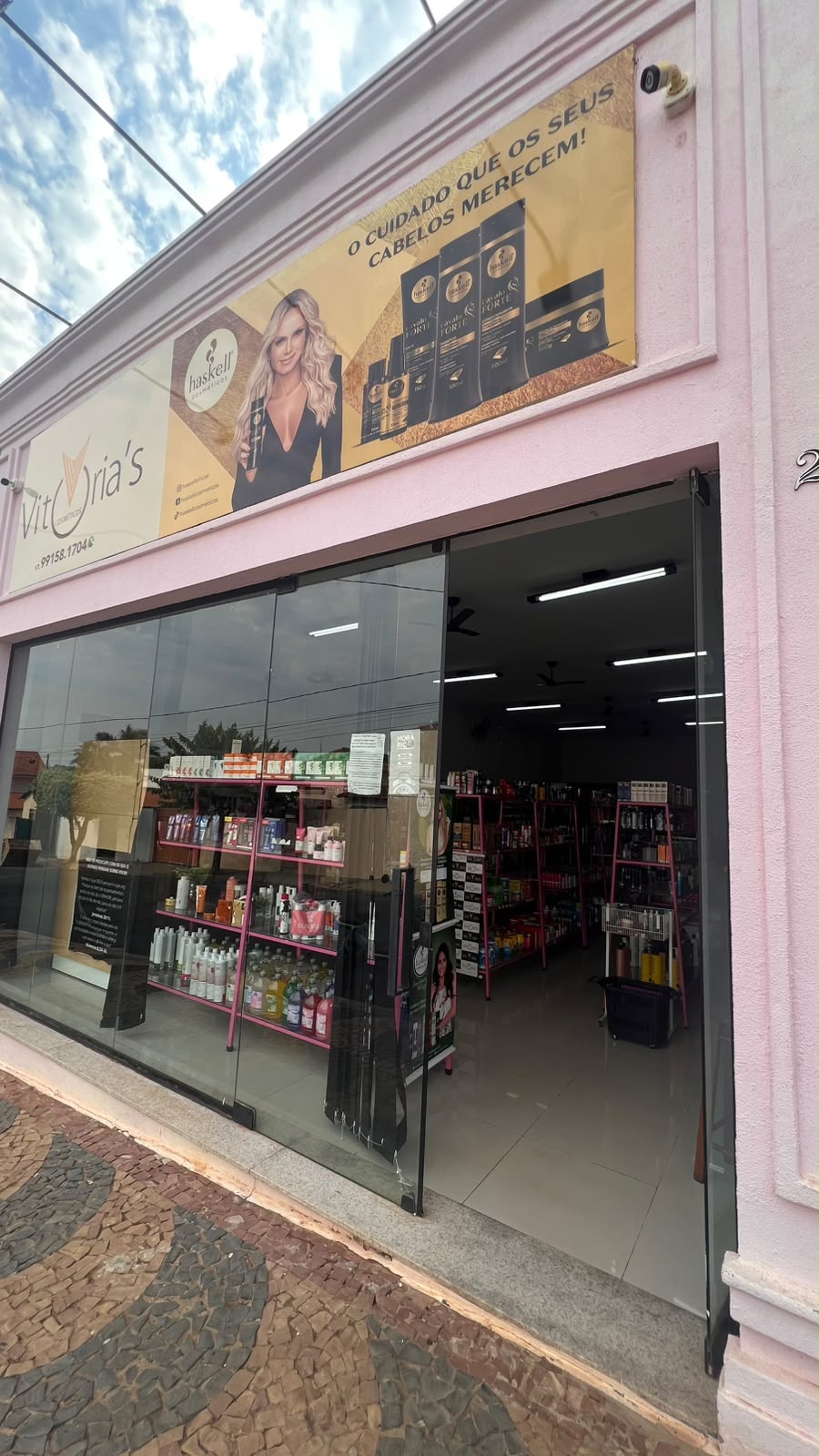 Fachada rosa da loja com vitrine de vidro e porta aberta